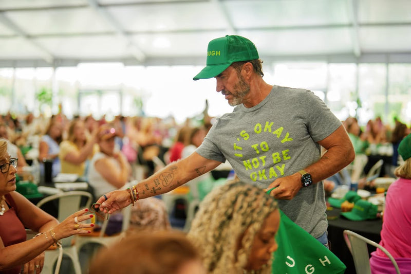 Blake Mycoskie handing an ENOUGH bracelet to an attendee
